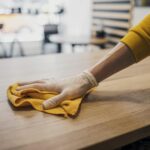 side-view-barista-cleaning-table-while-wearing-latex-glove
