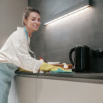 Chores. Young dark-haired woman cleaning the surfaces in the kitchen